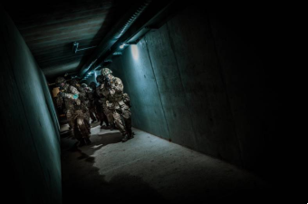 armed soldiers running through a dark tunnel